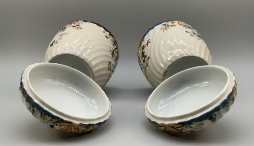 fig 8. A pair of 19th-century Japanese cream porcelain lidded jars featuring spiralled fluted bodies and hand-painted polychrome floral decoration with sculpted finials.
