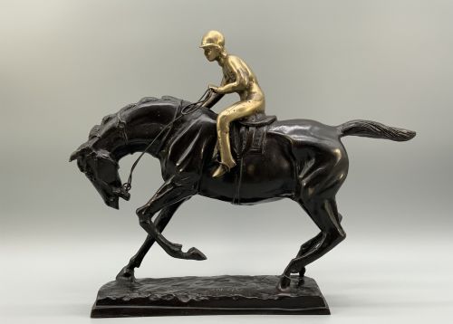 fig 3. A patinated bronze sculpture depicting a racehorse and jockey mid-stride set upon a textured rectangular bronze base.