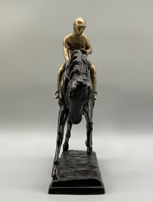 fig 5. A patinated bronze sculpture depicting a racehorse and jockey mid-stride set upon a textured rectangular bronze base.