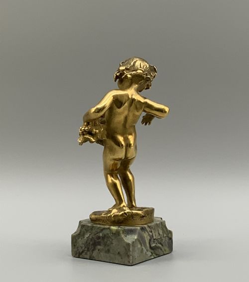 fig 5. A small gilt bronze sculpture depicting an infant Bacchus holding a bunch of grapes, set upon a square green marble plinth.