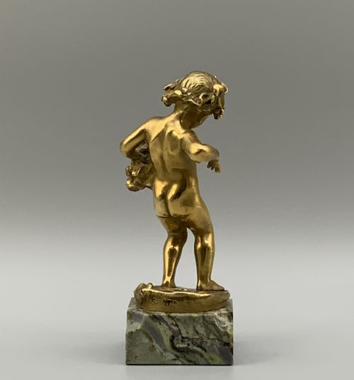 fig 6. A small gilt bronze sculpture depicting an infant Bacchus holding a bunch of grapes, set upon a square green marble plinth.
