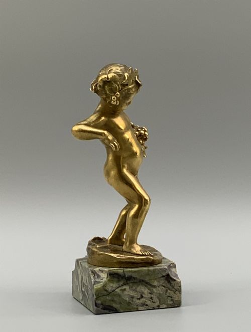 fig 7. A small gilt bronze sculpture depicting an infant Bacchus holding a bunch of grapes, set upon a square green marble plinth.