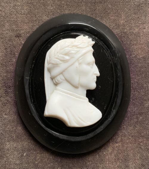 fig 3. A small carved white classical profile portrait cameo mounted on a dark background within a deep black ebonised square frame.