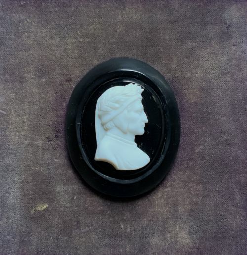 fig 4. A small carved white classical profile portrait cameo mounted on a dark background within a deep black ebonised square frame.