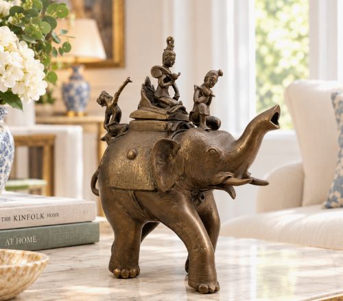 fig 1. A dark bronze 19th-century sculpture depicting an elephant with engraved decorative trappings and riders seated on its back.