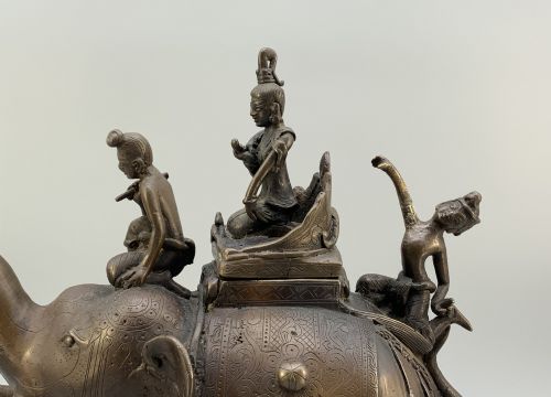 fig 4. A dark bronze 19th-century sculpture depicting an elephant with engraved decorative trappings and riders seated on its back.