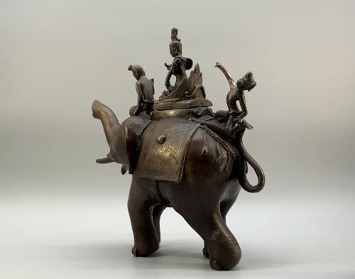 fig 5. A dark bronze 19th-century sculpture depicting an elephant with engraved decorative trappings and riders seated on its back.