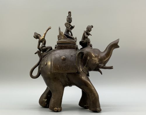 fig 7. A dark bronze 19th-century sculpture depicting an elephant with engraved decorative trappings and riders seated on its back.