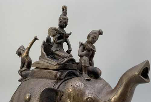 fig 10. A dark bronze 19th-century sculpture depicting an elephant with engraved decorative trappings and riders seated on its back.