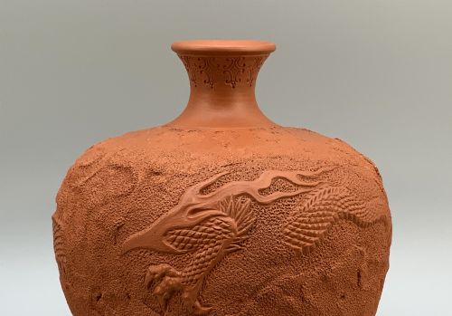 fig 4. A pair of unglazed terracotta red clay vases featuring detailed relief carvings of dragons with narrow flared necks.
