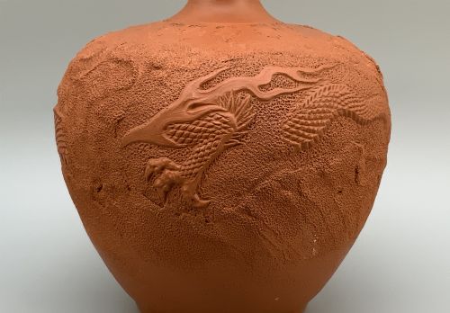 fig 5. A pair of unglazed terracotta red clay vases featuring detailed relief carvings of dragons with narrow flared necks.
