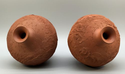 fig 7. A pair of unglazed terracotta red clay vases featuring detailed relief carvings of dragons with narrow flared necks.