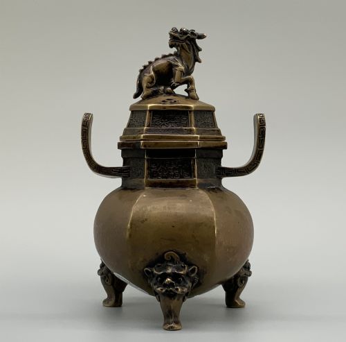 fig 2. A late Qing dynasty hexagonal bronze tripod censer featuring upright side handles, a removable cover topped with a mythical beast finial, and feet shaped as animal masks.
