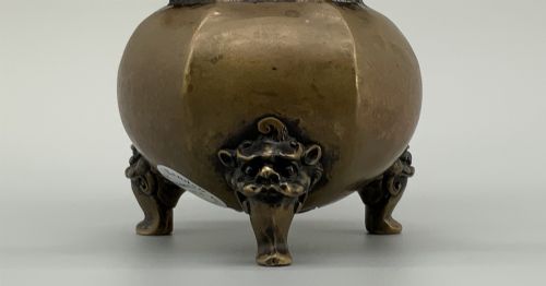 fig 4. A late Qing dynasty hexagonal bronze tripod censer featuring upright side handles, a removable cover topped with a mythical beast finial, and feet shaped as animal masks.