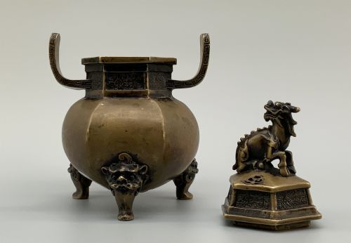 fig 5. A late Qing dynasty hexagonal bronze tripod censer featuring upright side handles, a removable cover topped with a mythical beast finial, and feet shaped as animal masks.