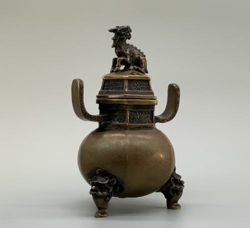 fig 7. A late Qing dynasty hexagonal bronze tripod censer featuring upright side handles, a removable cover topped with a mythical beast finial, and feet shaped as animal masks.