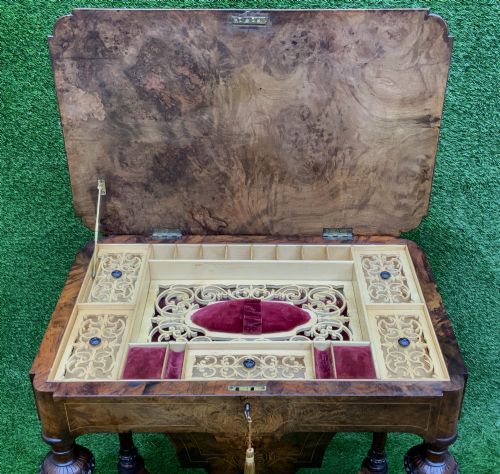 fig 4. A 19th-century burr walnut work table featuring a green leather inset top, floral marquetry inlay, turned legs, and a hanging storage pouch.