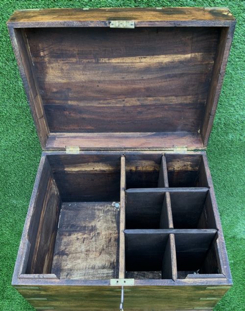 fig 5. A dark teak Anglo-Indian wine cellarette box with brass corner mounts resting on a carved turned-leg wooden stand.