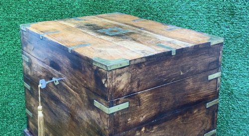 fig 6. A dark teak Anglo-Indian wine cellarette box with brass corner mounts resting on a carved turned-leg wooden stand.