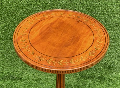 fig 3. A 19th-century satinwood wine table featuring a circular top with inlaid marquetry detailing, supported by a fluted central pedestal and three downswept tripod legs.
