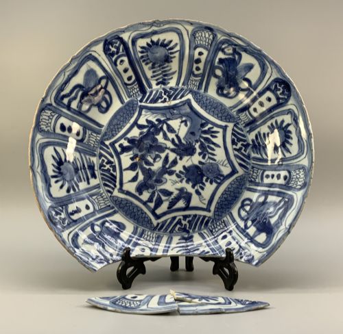 fig 1. A large 17th-century Japanese Edo period blue and white porcelain charger featuring panelled floral patterns with detached rim fragments in the foreground.