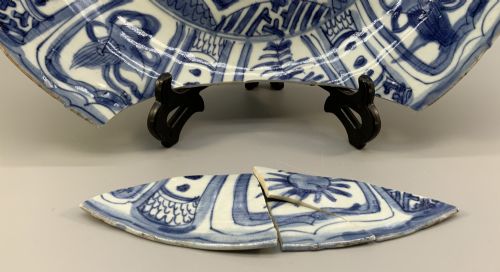 fig 3. A large 17th-century Japanese Edo period blue and white porcelain charger featuring panelled floral patterns with detached rim fragments in the foreground.