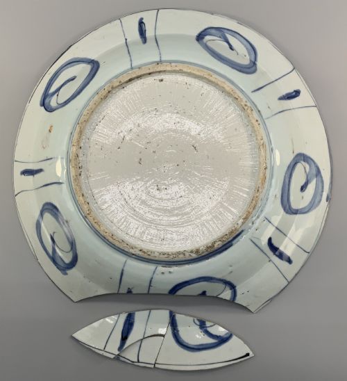 fig 9. A large 17th-century Japanese Edo period blue and white porcelain charger featuring panelled floral patterns with detached rim fragments in the foreground.