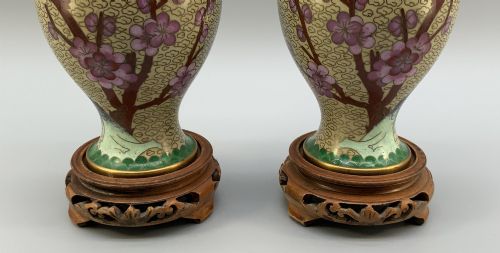 fig 5. A pair of early 20th-century Chinese cloisonne enamel vases featuring pink prunus blossoms and bird motifs on a yellow cloud-scroll ground, resting on carved wooden stands.