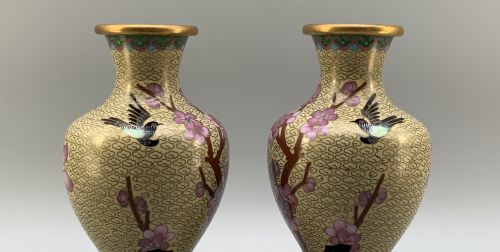fig 7. A pair of early 20th-century Chinese cloisonne enamel vases featuring pink prunus blossoms and bird motifs on a yellow cloud-scroll ground, resting on carved wooden stands.