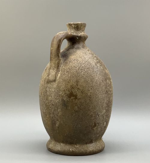 fig 3. A 19th-century salt-glazed stoneware flagon featuring a mottled brown textured surface, narrow neck, flared rim, and a single loop handle.