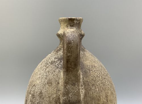 fig 5. A 19th-century salt-glazed stoneware flagon featuring a mottled brown textured surface, narrow neck, flared rim, and a single loop handle.
