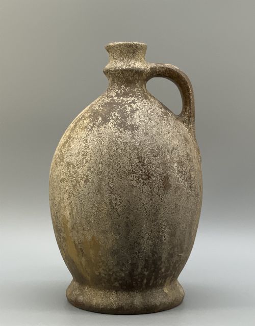 fig 7. A 19th-century salt-glazed stoneware flagon featuring a mottled brown textured surface, narrow neck, flared rim, and a single loop handle.