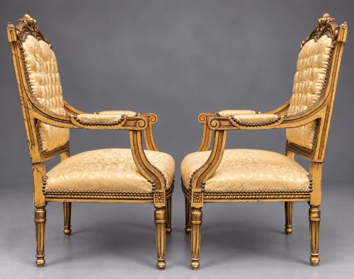 fig 2. A pair of 19th-century giltwood open armchairs featuring carved leaf detailing, button-tufted gold damask upholstery, and fluted front legs.