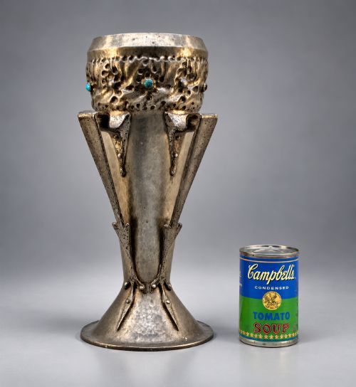 fig 1. An Arts and Crafts hammered pewter vase featuring raised geometric support fins, a textured upper band, and inlaid turquoise cabochons.
