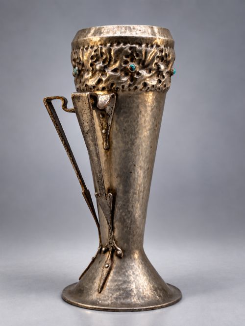 fig 2. An Arts and Crafts hammered pewter vase featuring raised geometric support fins, a textured upper band, and inlaid turquoise cabochons.