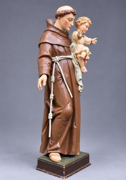 fig 1. An antique polychrome carved wood sculpture depicting Saint Anthony in a brown Franciscan habit holding the Christ Child.