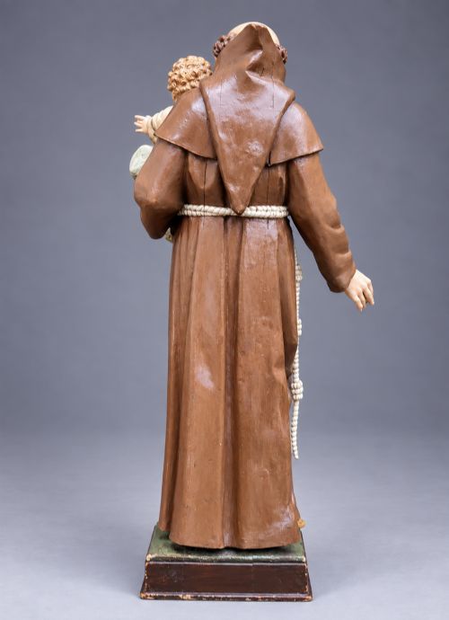 fig 4. An antique polychrome carved wood sculpture depicting Saint Anthony in a brown Franciscan habit holding the Christ Child.