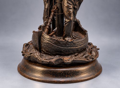 fig 7. A nineteenth-century dark patinated bronze sculpture depicting two fishermen standing in a small vessel atop sculpted ocean waves, mounted on a rounded base.