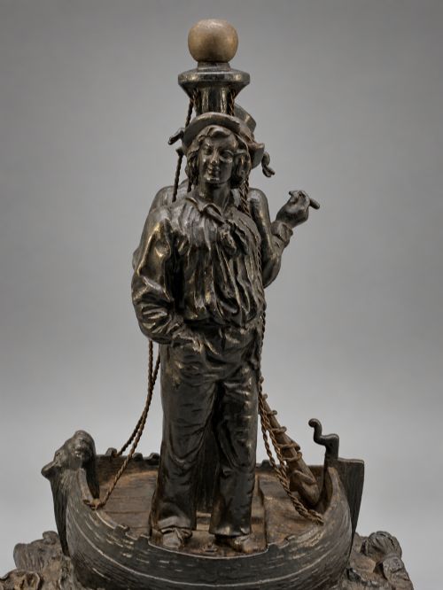fig 9. A nineteenth-century dark patinated bronze sculpture depicting two fishermen standing in a small vessel atop sculpted ocean waves, mounted on a rounded base.