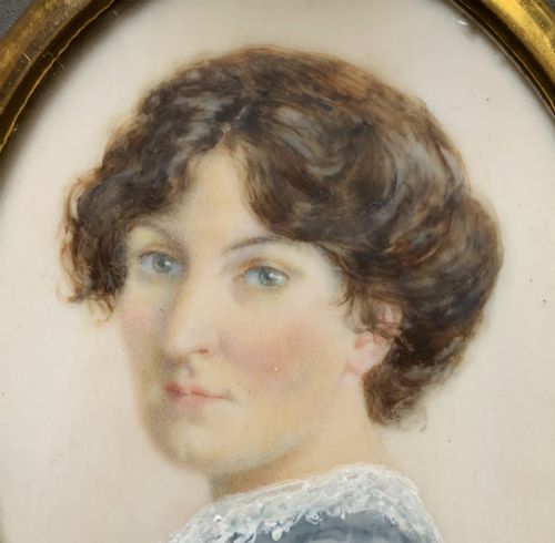 fig 3. An Edwardian oval watercolour portrait miniature depicting a lady with dark curly hair and a lace-collared blue dress, set within a gilt brass frame with a hanging ring.