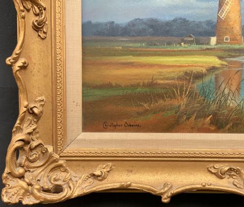 fig 8. An oil painting depicting Horsey Mill set amidst the Norfolk Broads under a cloud-filled sky, presented in an elaborate gilded swept frame.