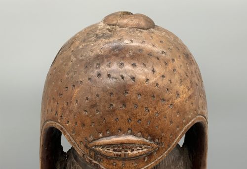 fig 9. A carved brown wooden African Mende Sowei staff finial depicting a stylised head with crest, mounted on a square black plinth.