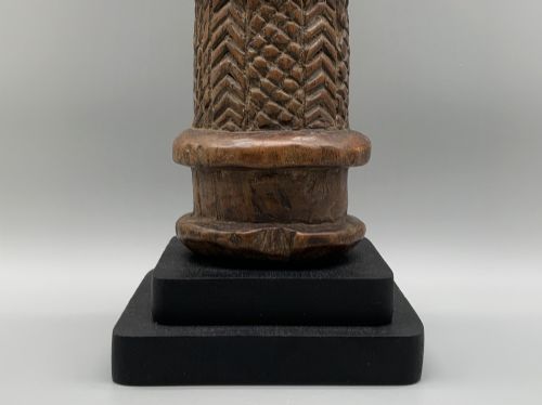 fig 10. A carved brown wooden African Mende Sowei staff finial depicting a stylised head with crest, mounted on a square black plinth.