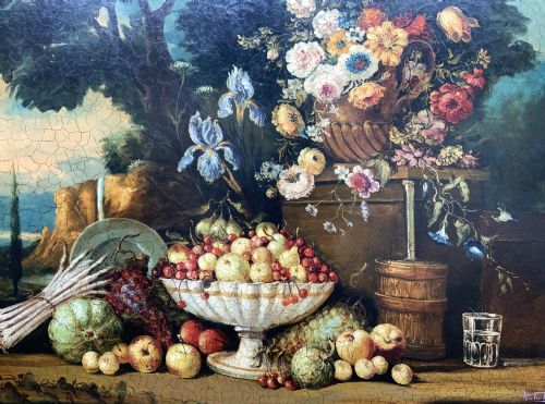 fig 4. A classical oil painting displaying a bowl of fruit, a urn with flowers, asparagus, and melons set against a dark landscape backdrop within a carved silver-grey frame.