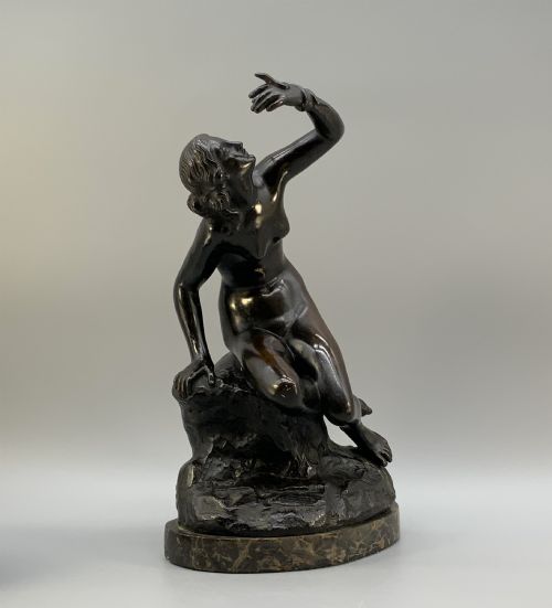 fig 3. A patinated dark bronze sculpture depicting a classical female figure reaching upward while seated on a rocky outcrop atop a circular marble base.