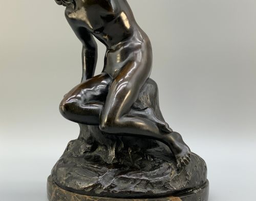 fig 9. A patinated dark bronze sculpture depicting a classical female figure reaching upward while seated on a rocky outcrop atop a circular marble base.