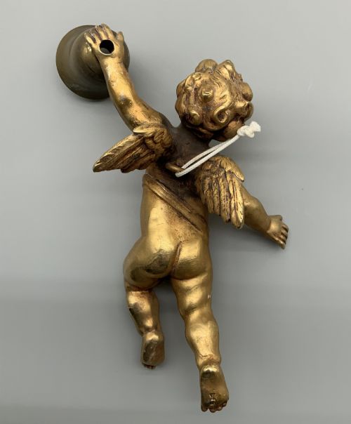 fig 5. A set of three gilt metal wall sconces crafted in the shape of winged cherubs holding bell-shaped light sockets.