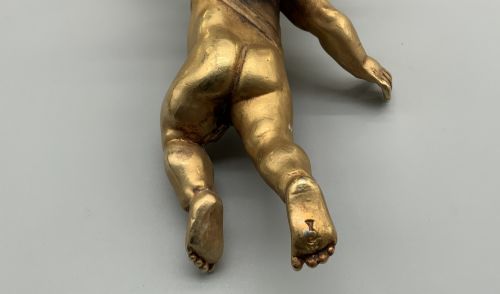 fig 7. A set of three gilt metal wall sconces crafted in the shape of winged cherubs holding bell-shaped light sockets.