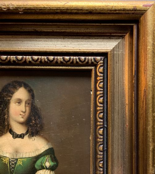 fig 7. A framed miniature oil portrait depicting a Victorian woman with dark curly hair in a green and red dress, enclosed in a gilded wooden frame with egg-and-dart detail.