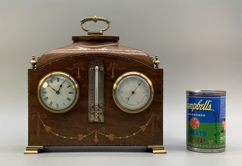 fig 1. An Edwardian mahogany desk compendium featuring an inlaid floral swag motif, central thermometer, clock dial, barometer dial, and top brass handle.